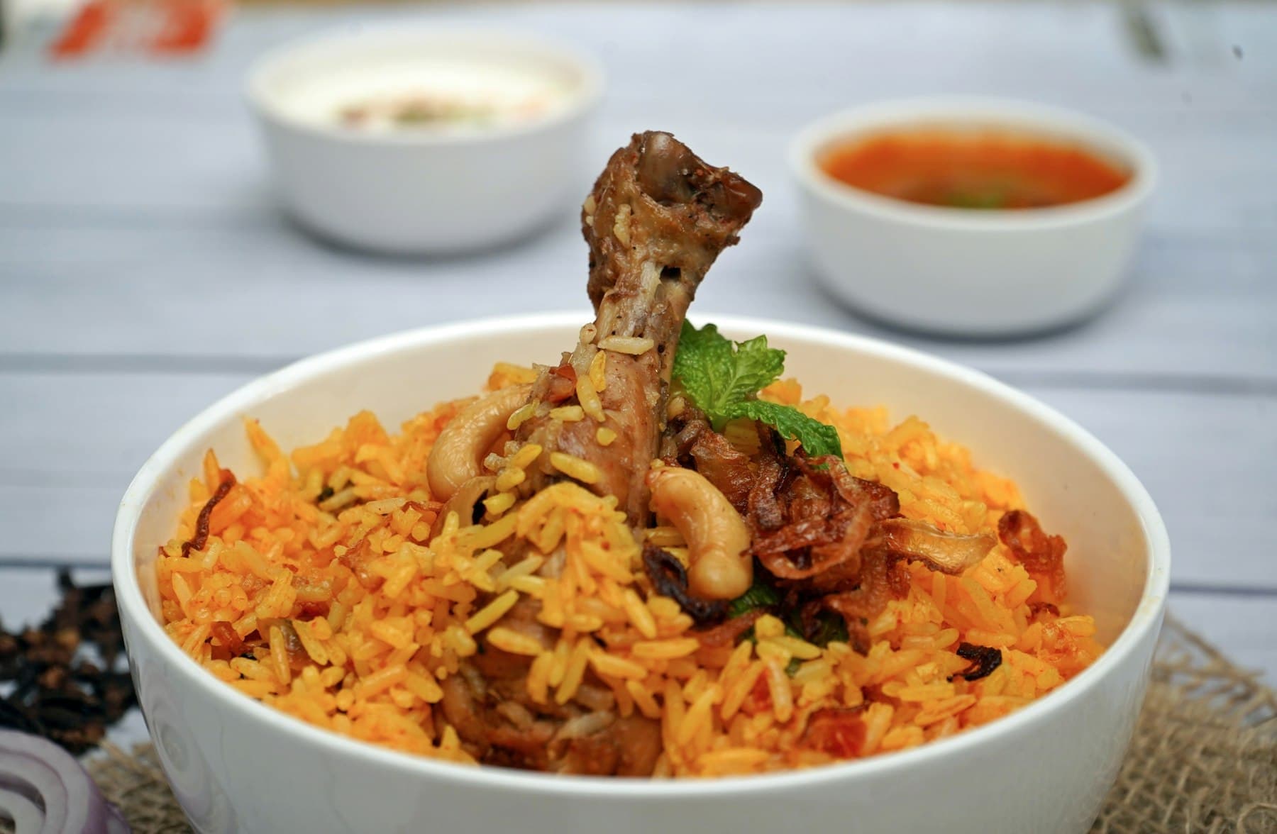 Bowl of chicken biryani with raita on the side