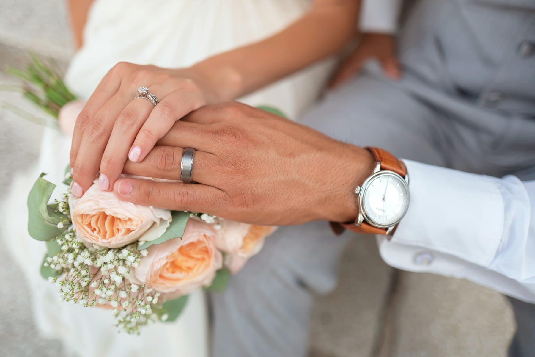 Newly married couple holding hands over a bouquet