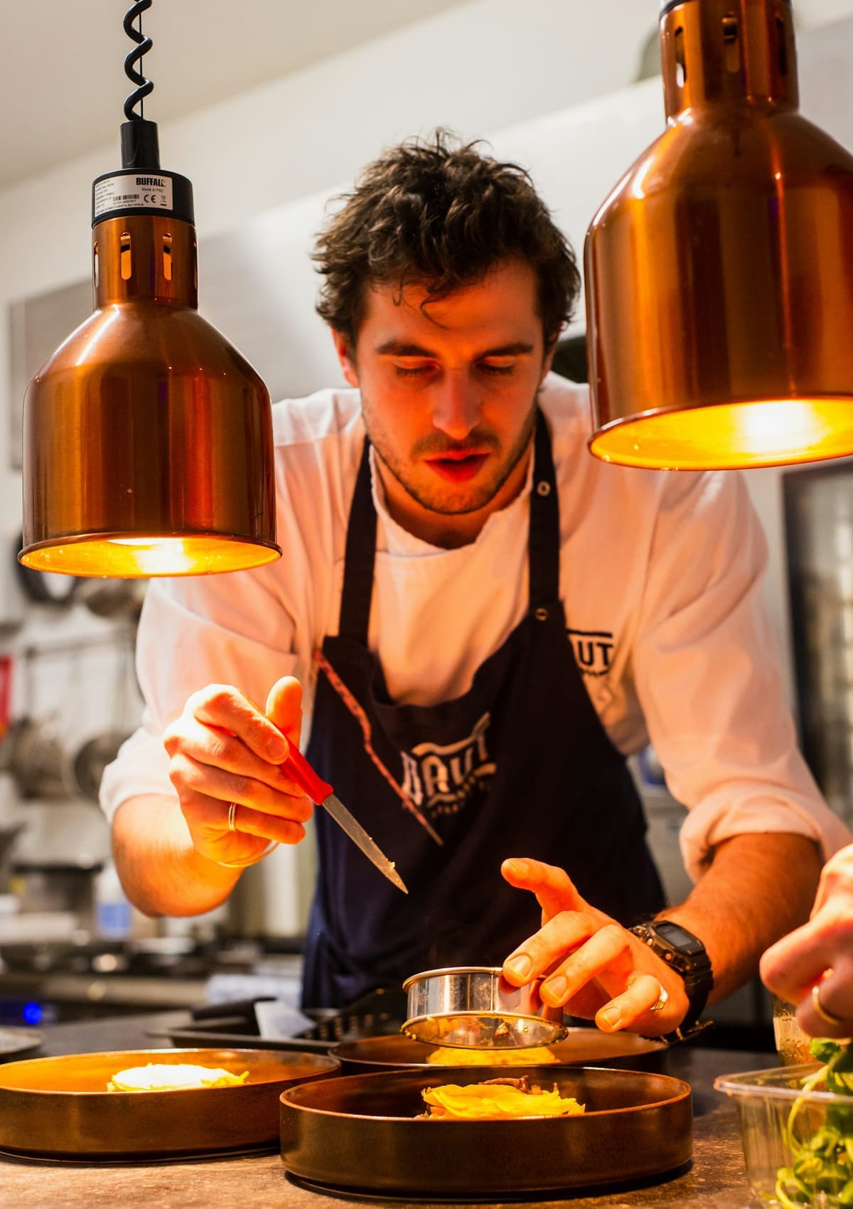 Chef carefully plating a dish under warm kitchen lights