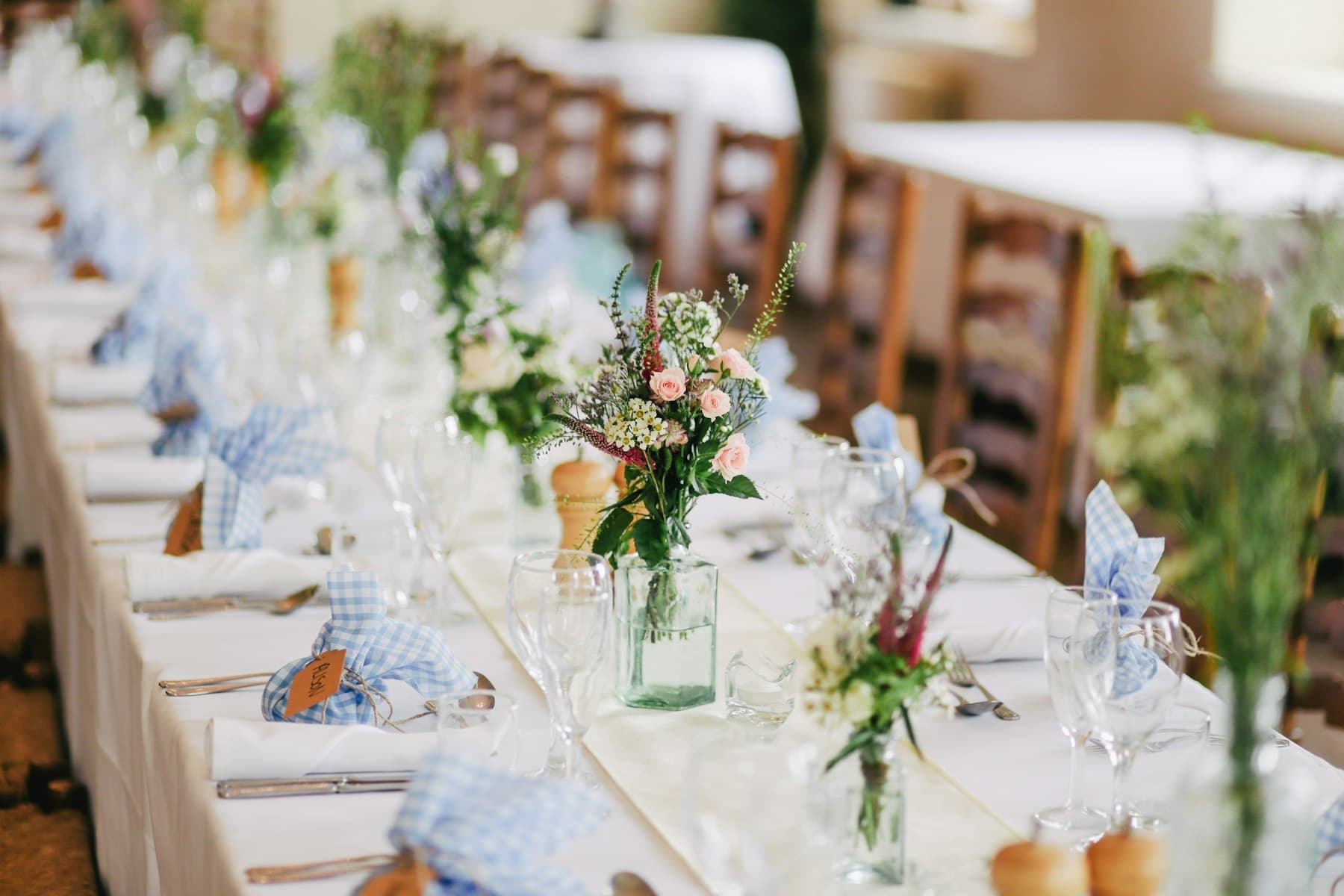 Long wedding banquet table dressed with flowers and white linen